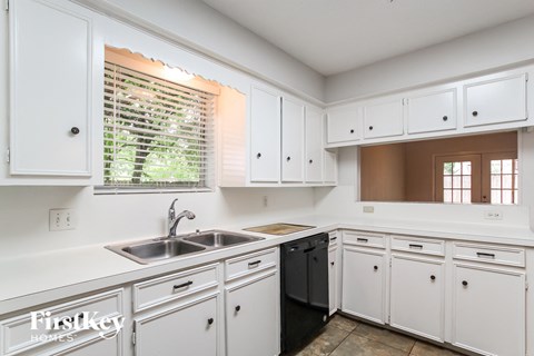 A kitchen with white cabinets and a black dishwasher.