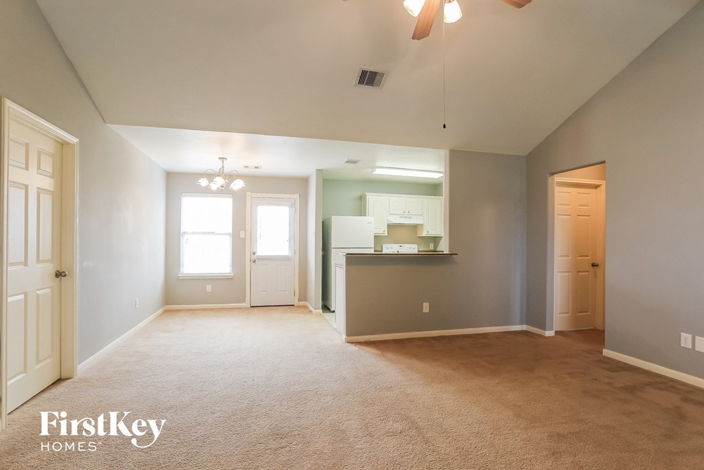 an empty living room and kitchen with a door to the bathroom