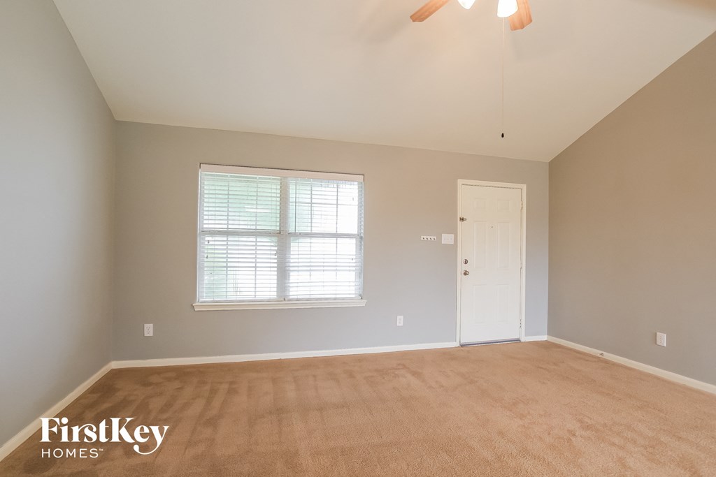 a empty living room with a white door and a window