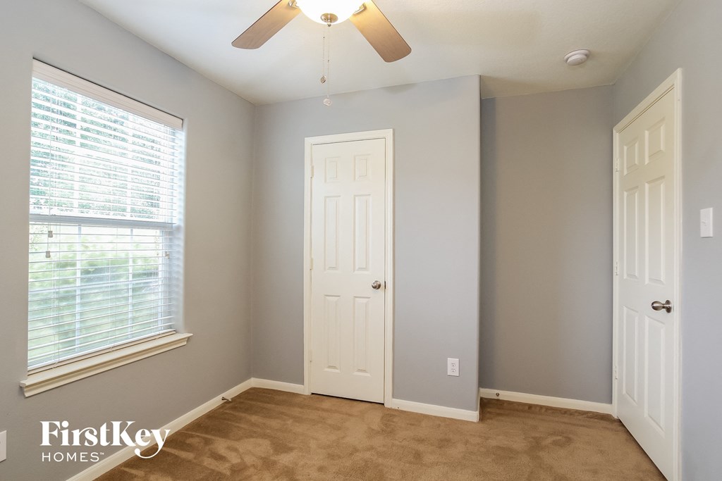 a bedroom with a white door and a window and a ceiling fan