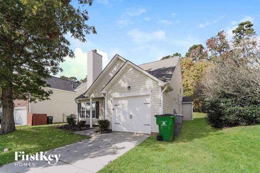 the front of a white house with a white garage door and a green yard