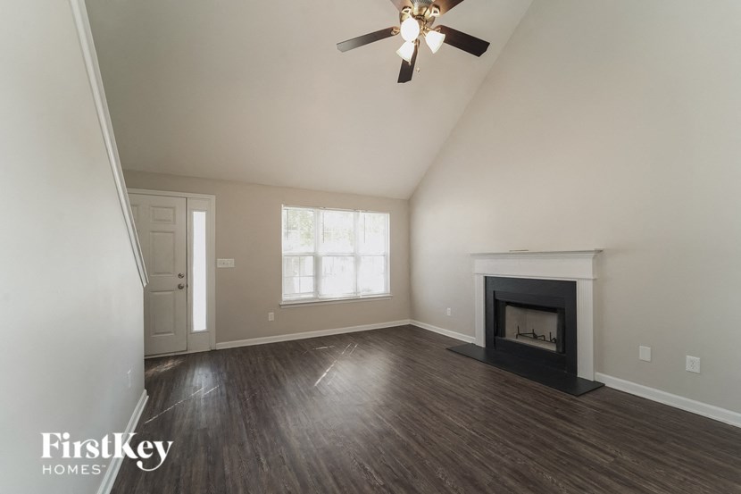 an empty living room with a fireplace and a ceiling fan