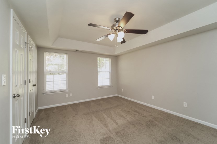 the spacious living room with ceiling fan and carpeting