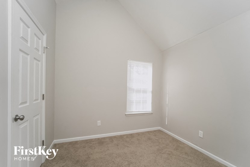 a bedroom with beige carpet and white walls and a window