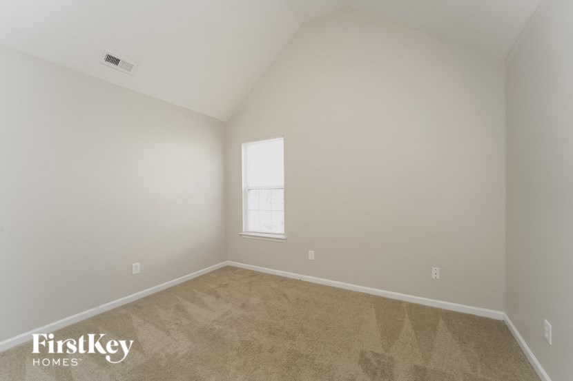 a bedroom with white walls and carpet and a window