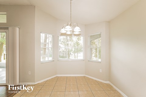 an empty dining room with three windows and a tiled floor