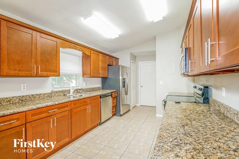 a kitchen with wooden cabinets and granite counter tops and a stainless steel refrigerator