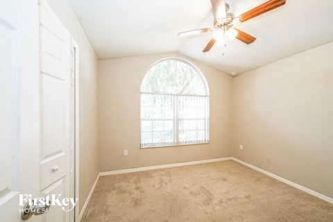 an empty bedroom with a large window and a ceiling fan