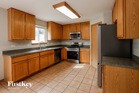 A kitchen with wooden cabinets and a black refrigerator.