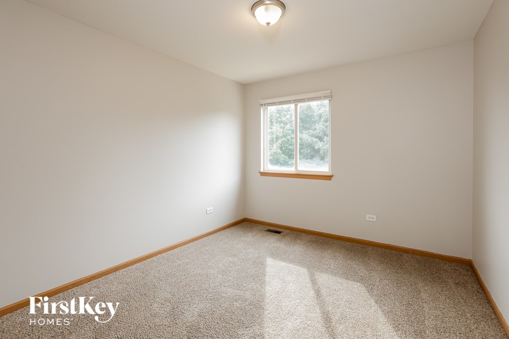 A carpeted room with a window and a light on the ceiling.