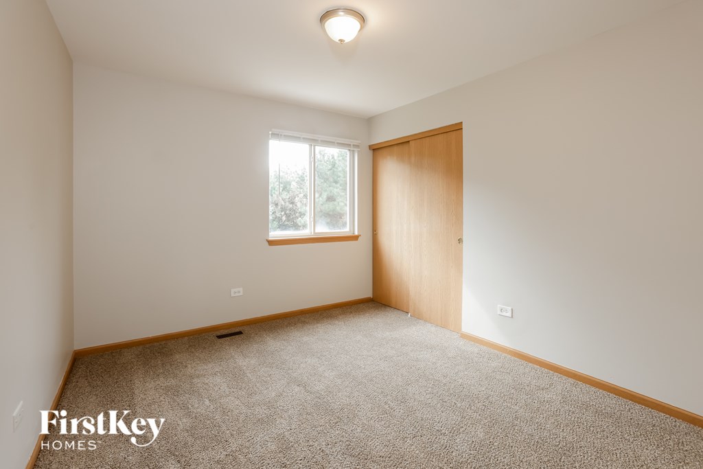 A carpeted room with a door and a window.