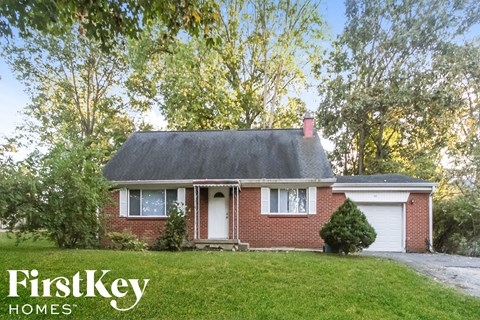 a small brick house with a gray roof on a lawn