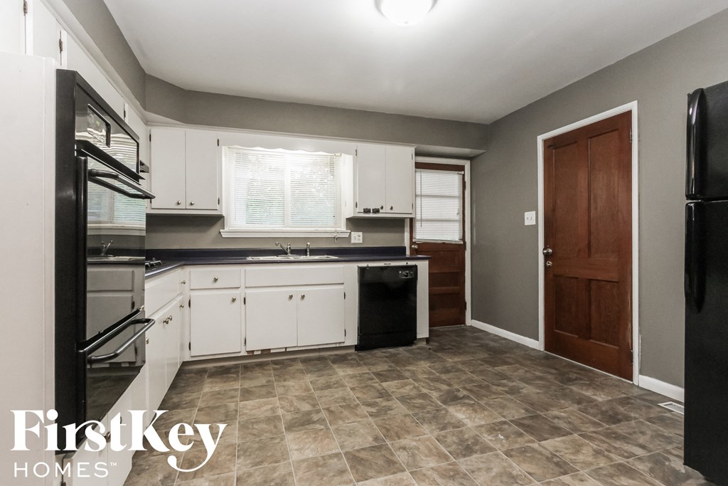 a kitchen with white cabinets and black appliances and a black refrigerator