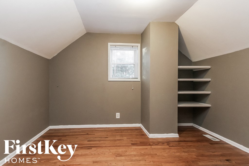 a room with a wood floor and a closet with shelves and a window