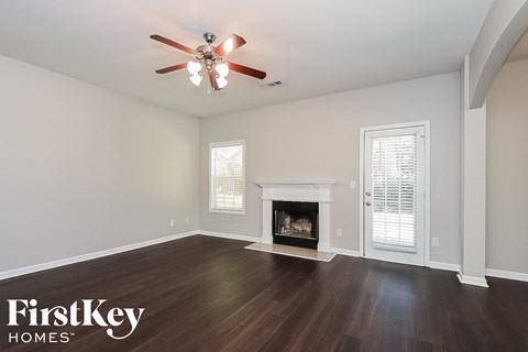 A spacious room with a fireplace and a ceiling fan.