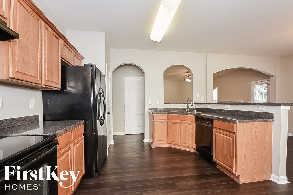 A kitchen with wooden cabinets and a black refrigerator.