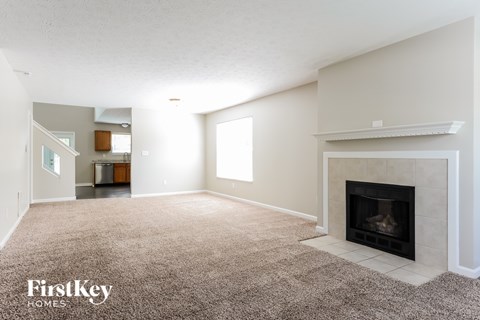 A living room with a fireplace and a carpet.