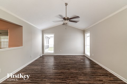 an empty living room with a ceiling fan and a window