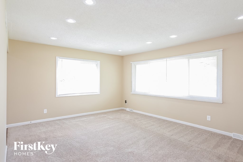 a white carpeted room with two windows