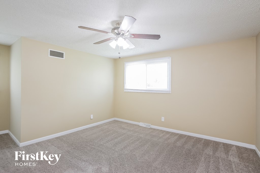 a carpeted room with a ceiling fan and a window