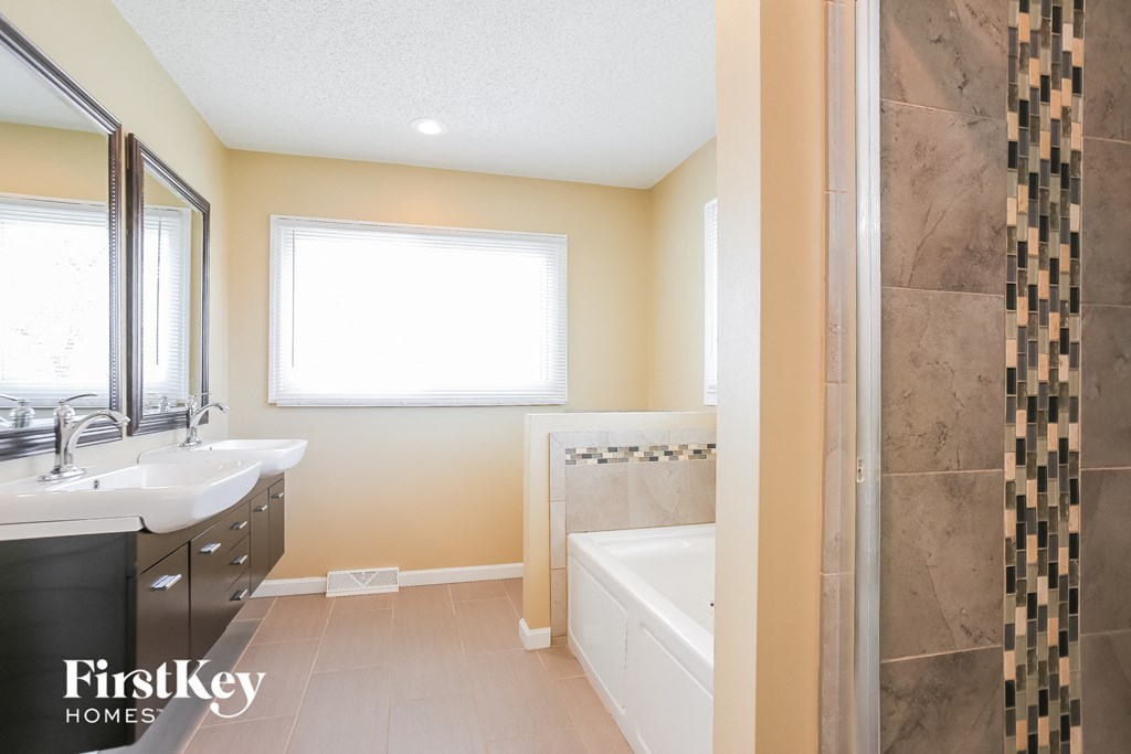 a bathroom with a tub and a sink and a mirror