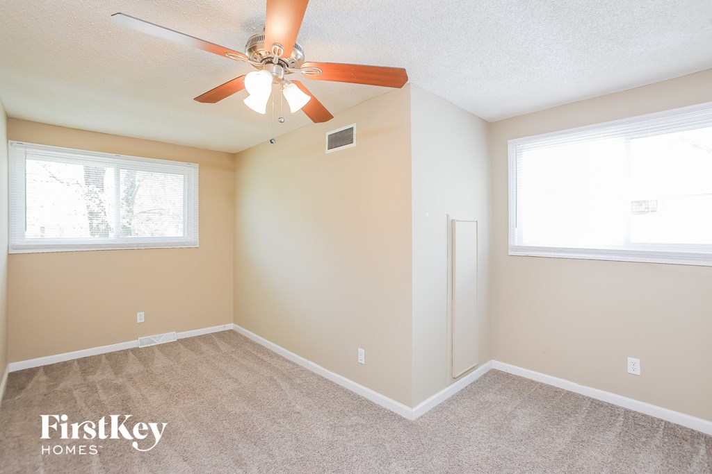 a bedroom with a ceiling fan and two windows