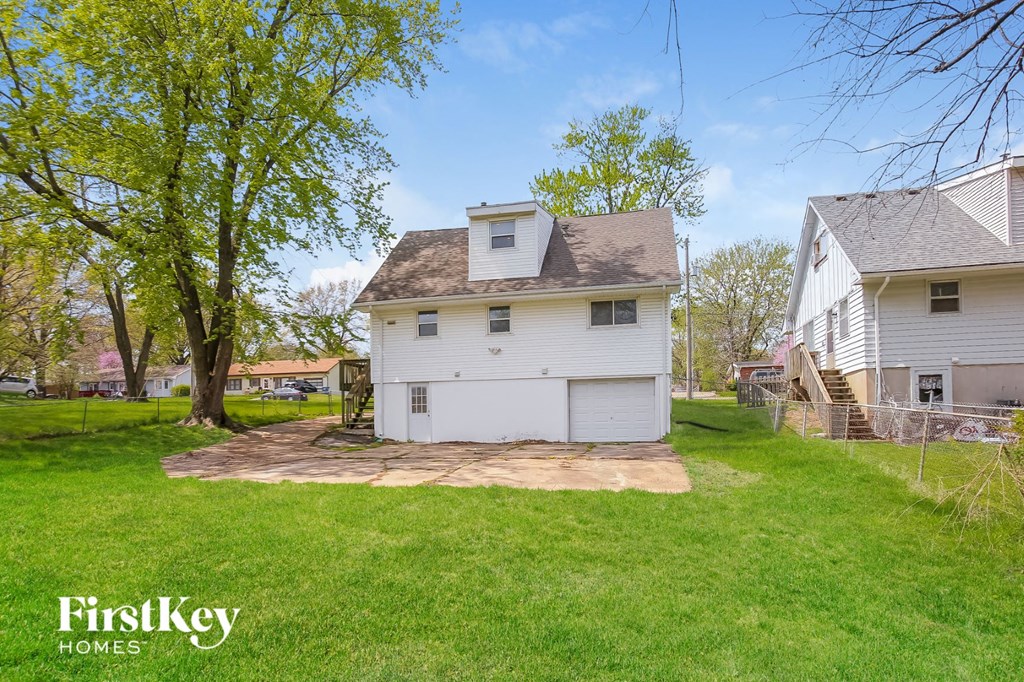 a backyard with a white house and a gravel driveway
