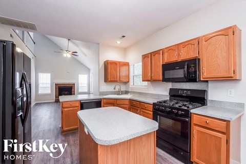 a kitchen with wood cabinets and black appliances and a white counter top