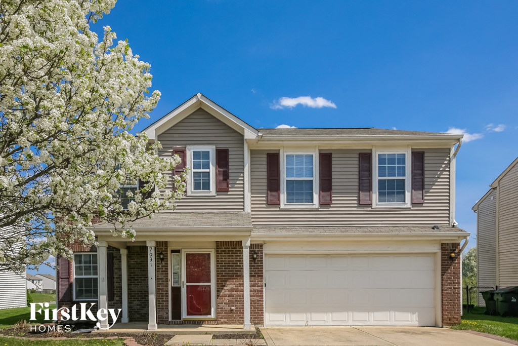 A house with a red door and a garage door is for sale.