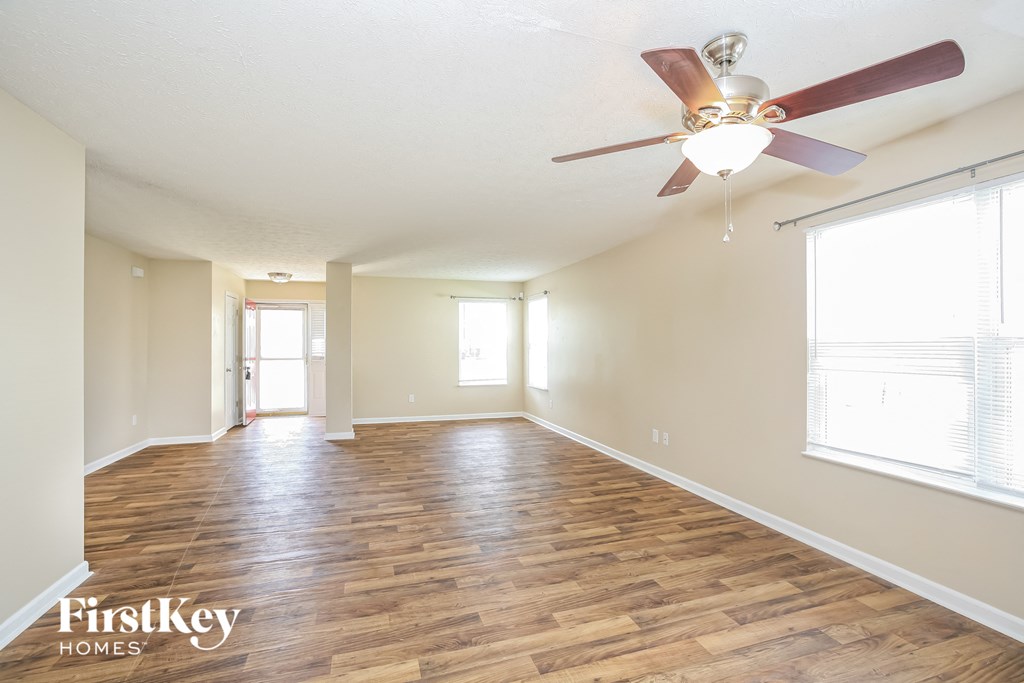 A spacious room with wooden floors and a ceiling fan.