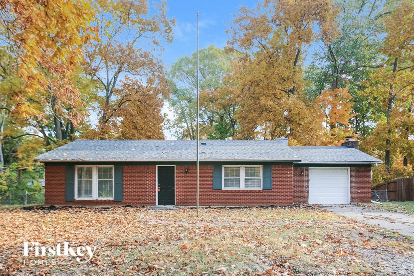 a small brick house in the fall with leaves on the ground