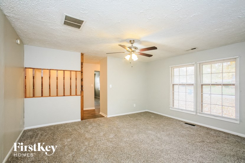 the living room of an empty house with a ceiling fan