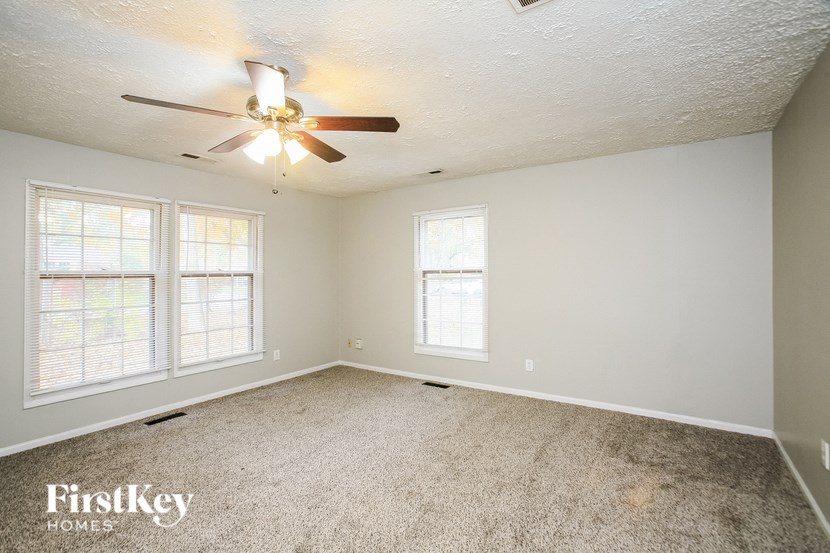 a bedroom with a ceiling fan and two windows