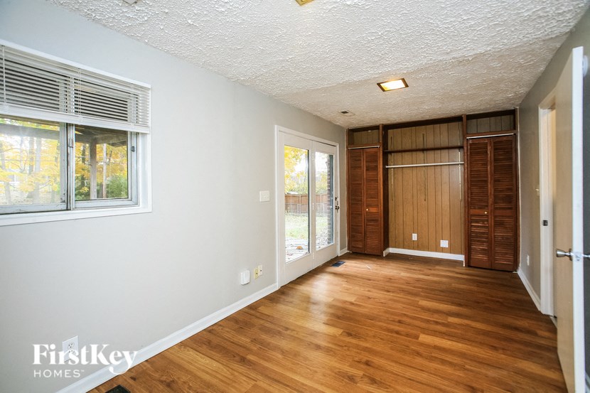 a living room with wood flooring and a door to a hallway with a window