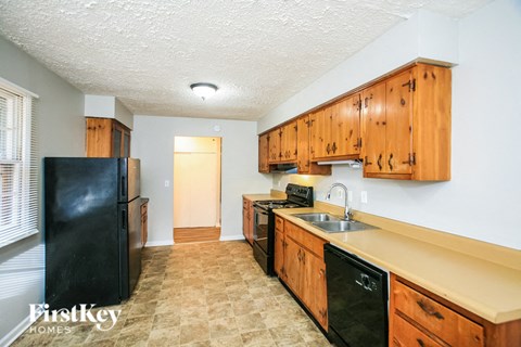 a kitchen with wooden cabinets and a black refrigerator and sink