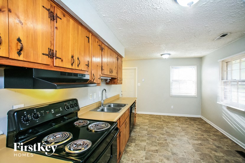 a kitchen with a stove and a sink and wooden cabinets