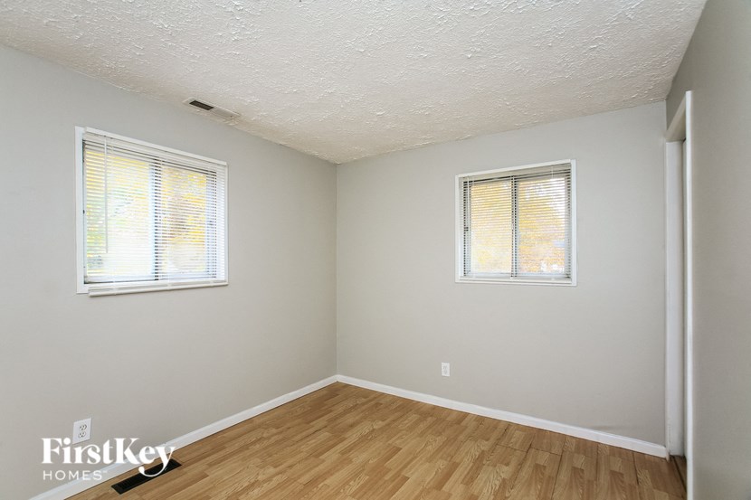 the living room of an empty house with wood flooring and two windows