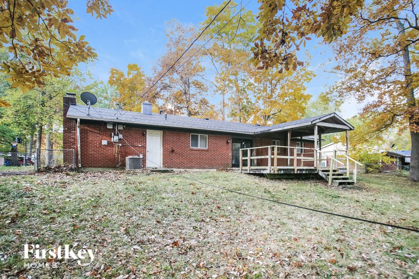 a small brick house with a yard and a fence