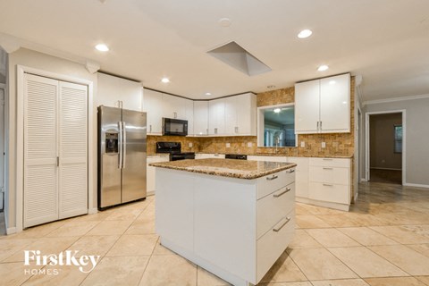 a large kitchen with white cabinets and a stainless steel refrigerator