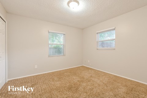 a bedroom with a carpeted floor and two windows