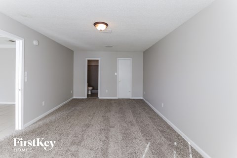 a spacious living room with gray carpet and white walls