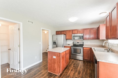 A kitchen with wooden cabinets and a stainless steel refrigerator.
