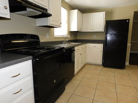 A black stove and oven in a kitchen with white cabinets.
