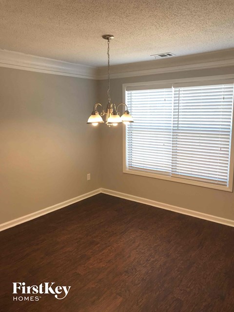 an empty dining room with a window and a chandelier