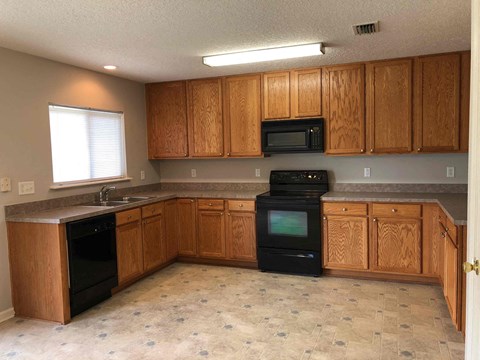 A kitchen with wooden cabinets and black appliances.
