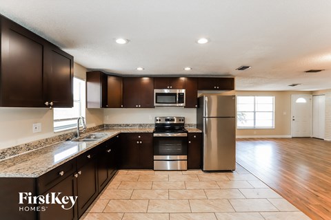 A kitchen with dark brown cabinets and a granite countertop.