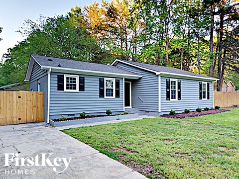 a small blue house with a yard and a wooden fence