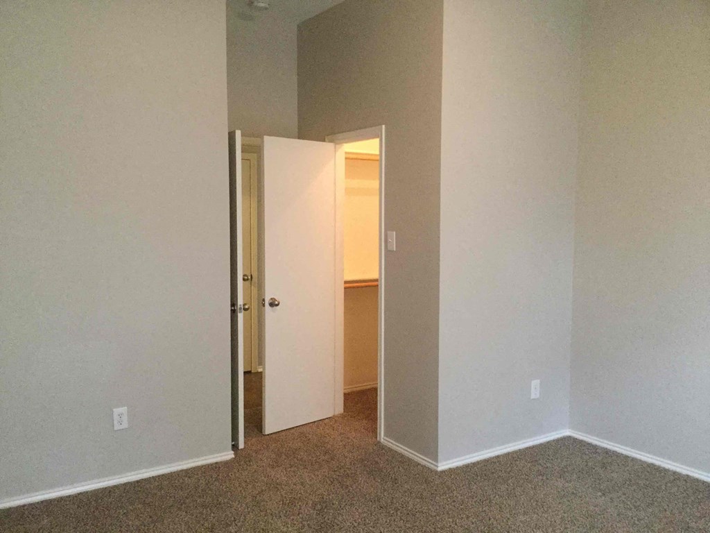 an empty bedroom with a door open to a closet