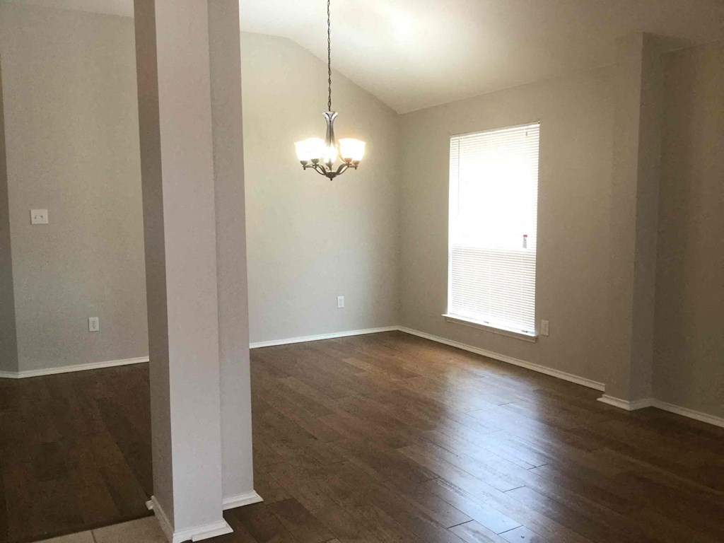 an empty living room with wood floors and a window