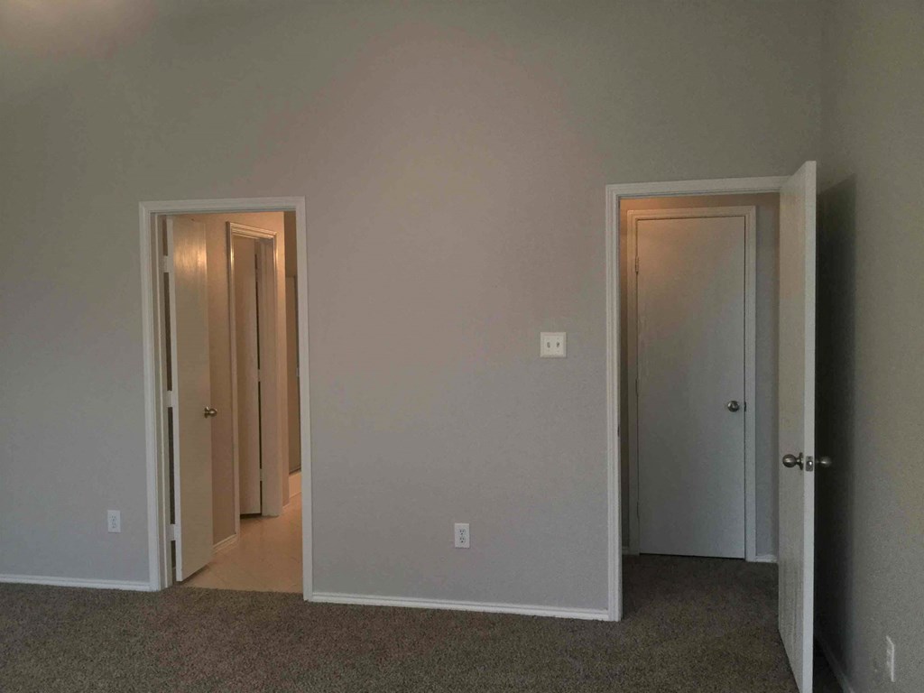 an empty room with three doors and a carpeted floor